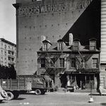 512-514 Broome Street. "Two row houses are dwarfed by the Grocers Warehouse Corporation building behind it, trucks in the foreground."